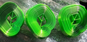 Three bright green, 3d printed fidget toys created from the leaf shaped Sprout Social logo.