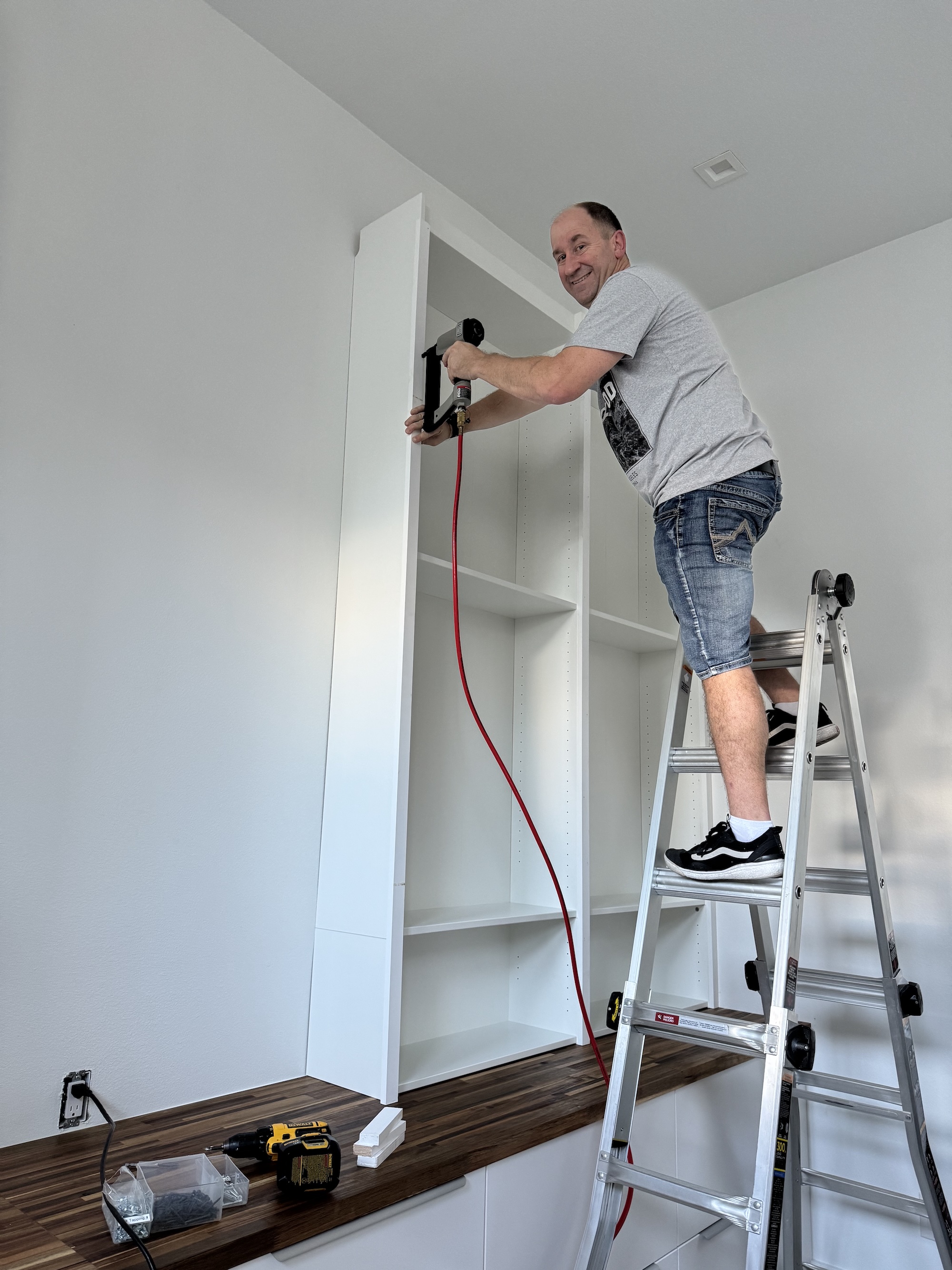Photo of me nailing trim pieces onto the front of the bookcases.